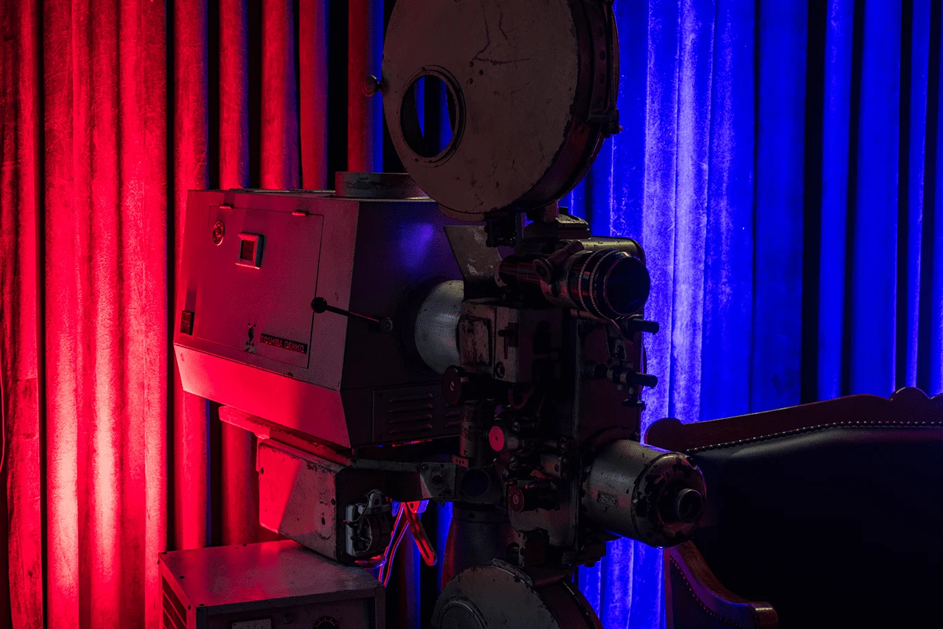 Detalle de un antiguo proyector de cine entre cortinas iluminadas a color